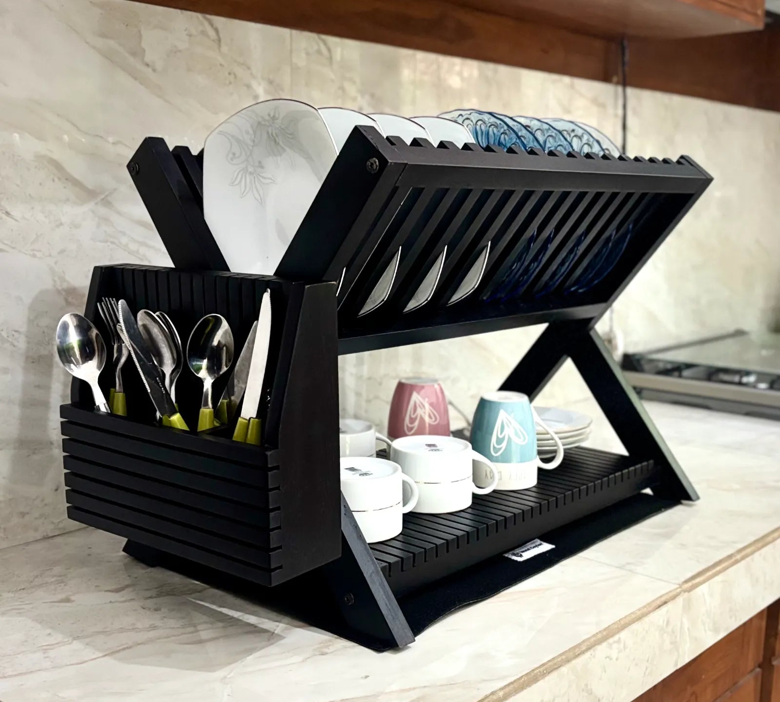 Wood Ceylon black wooden dish drying rack with two tiers holding plates, cups, and utensils on a kitchen counter