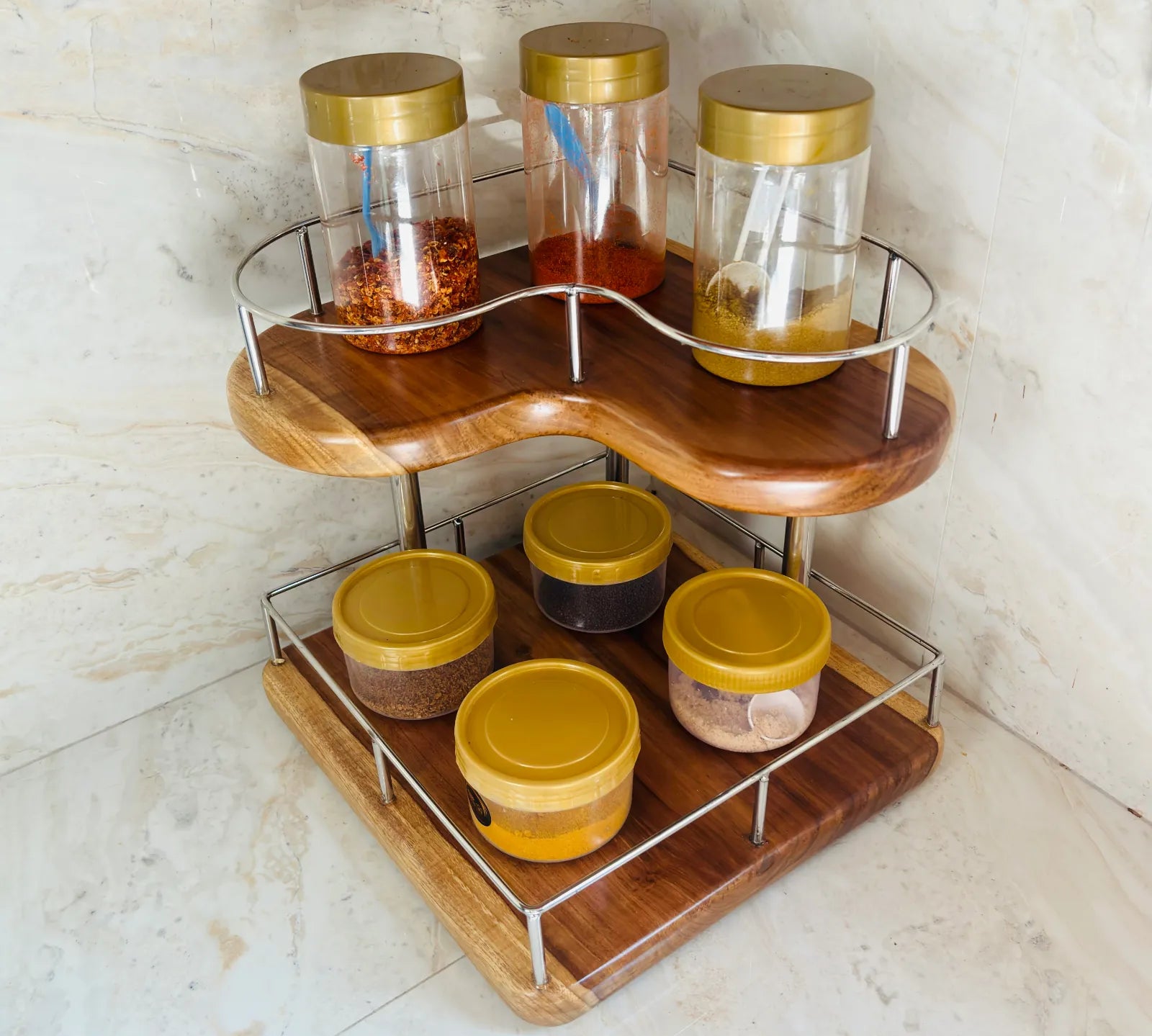 Wood Ceylon corner spice rack with two-tier wooden shelves and metal railing holding jars with gold lids