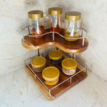 Wood Ceylon corner spice rack with two-tier wooden shelves and metal railing holding jars with gold lids
