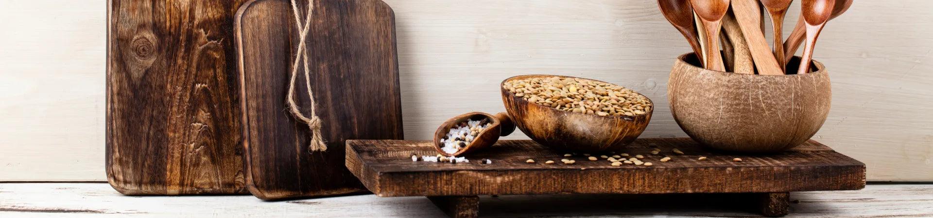 Handmade teak wood kitchen accessories including cutting boards and wooden utensils displayed on a rustic surface