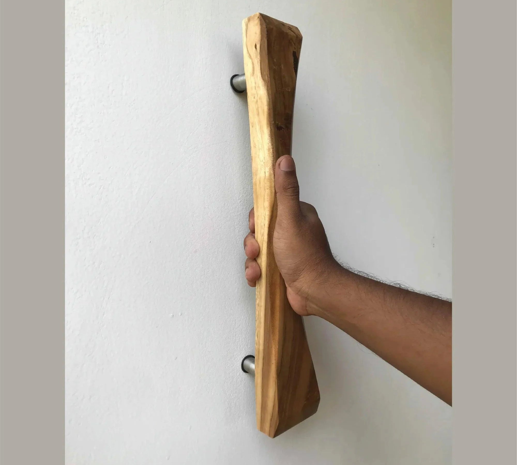 Wooden sliding door handle being held by a hand mounted on a white wall by Wood Ceylon