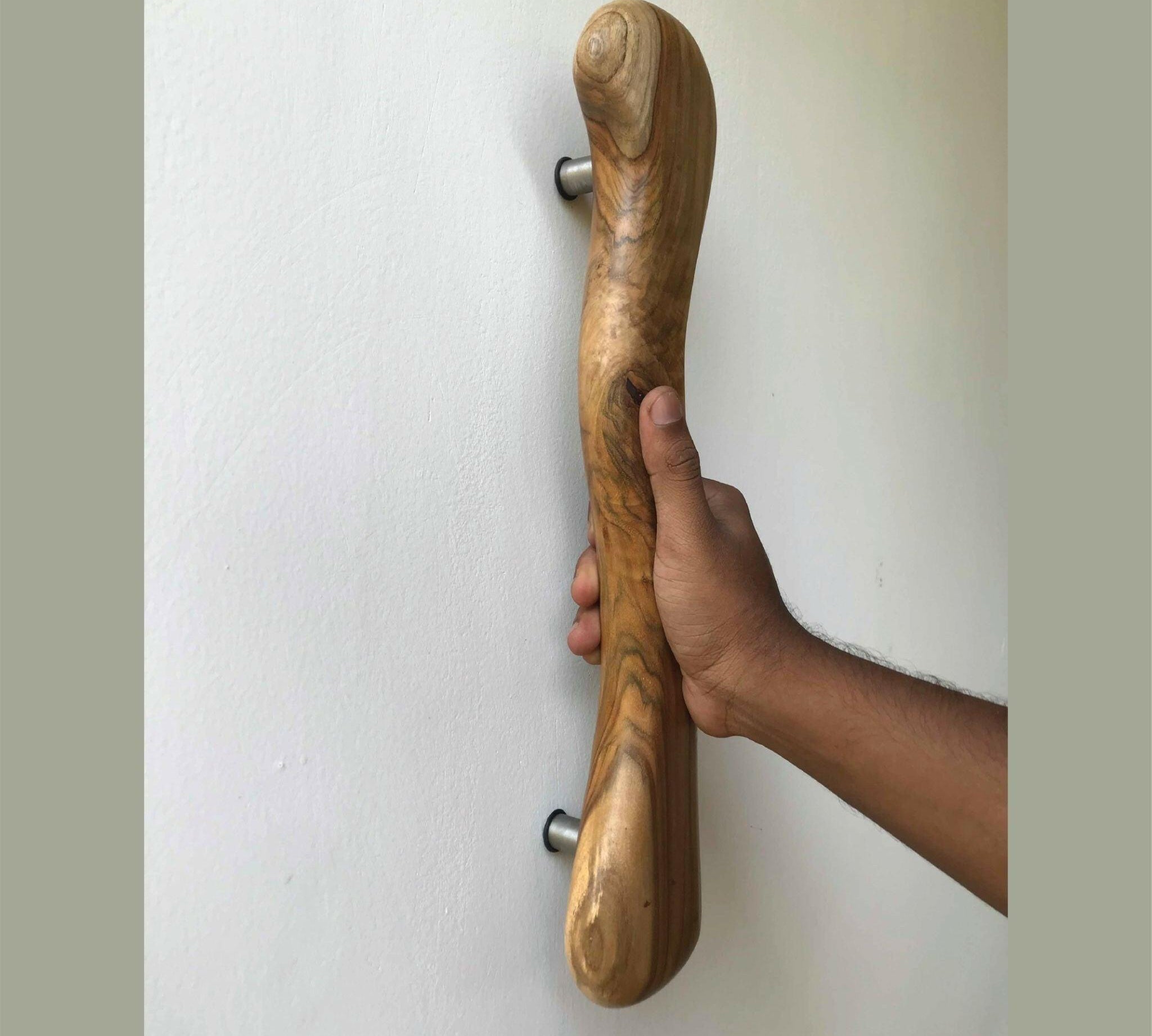Wood Ceylon wooden door handle mounted on white wall held by hand