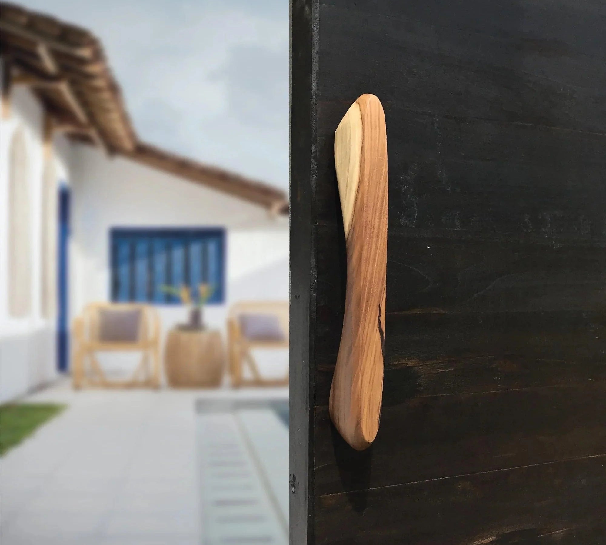 Wood Ceylon wooden front door handle hardware mounted on a dark door with a blurred outdoor background