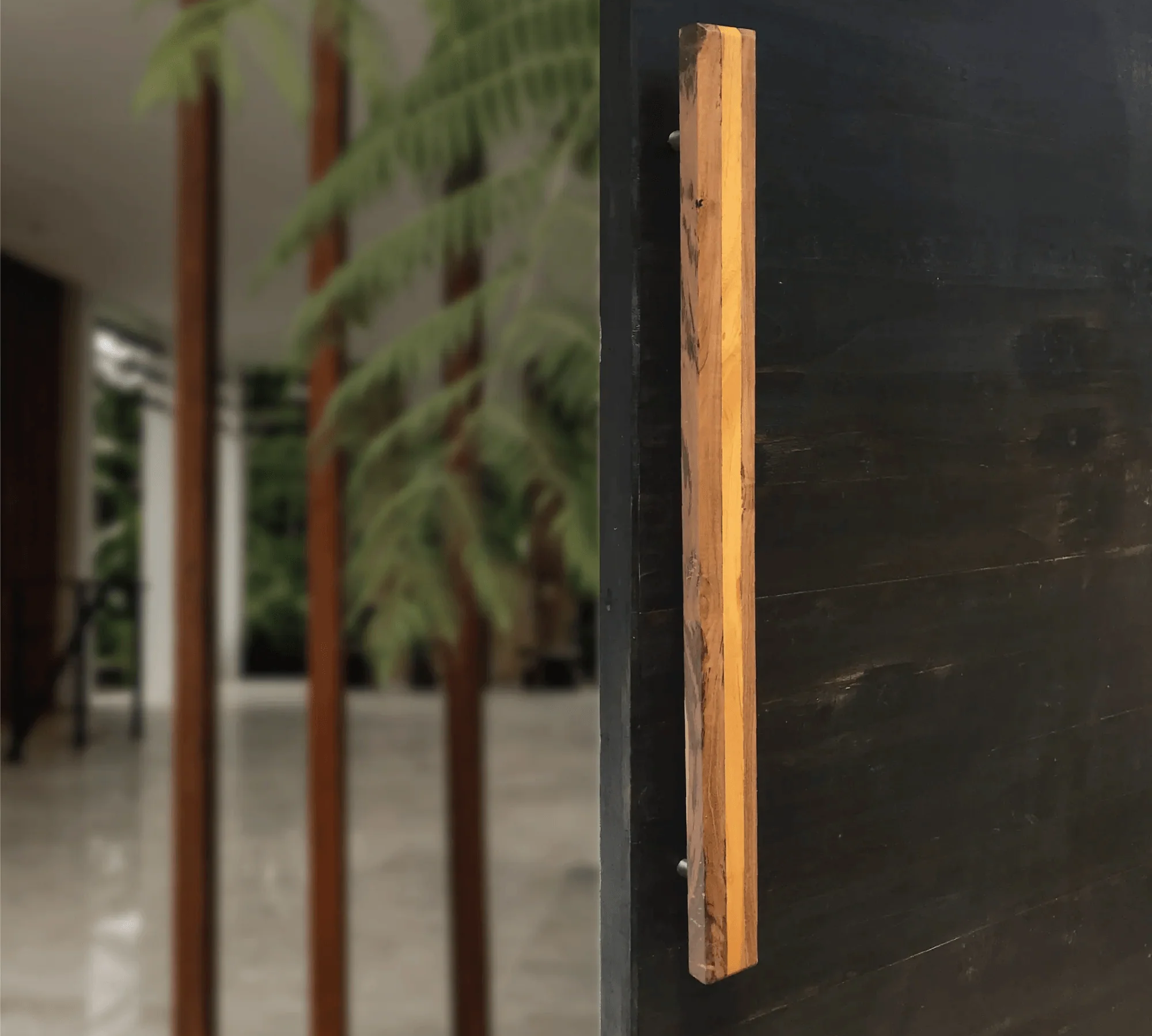 Large wooden door handle mounted on a dark door showcasing natural wood texture by Wood Ceylon